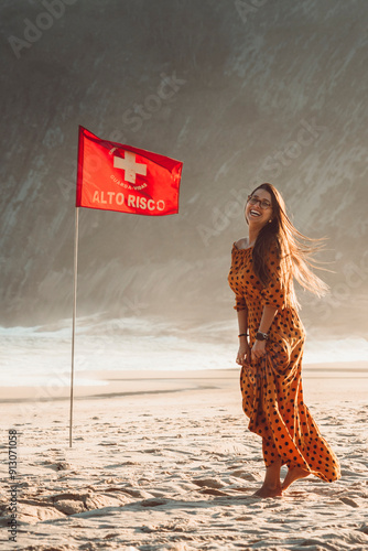 Beautiful brunette girl model smiling beside tide warning flag at the beach