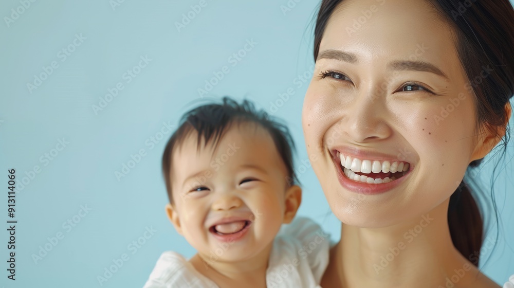 Asian mother adoringly gazes at her smiling baby, showcasing their deep bond in a light studio. Asian mother adoringly gazes at her smiling baby, showcasing their deep bond in a light studio.