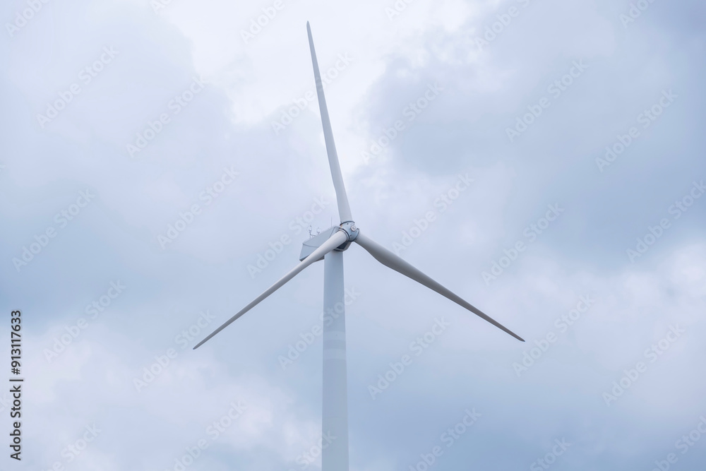 Wind turbine against a cloudy sky showcasing renewable energy technology and sustainability in a natural, overcast environment. Wind turbine against a cloudy sky showcasing renewable energy technology and sustainability in a natural, overcast environment.