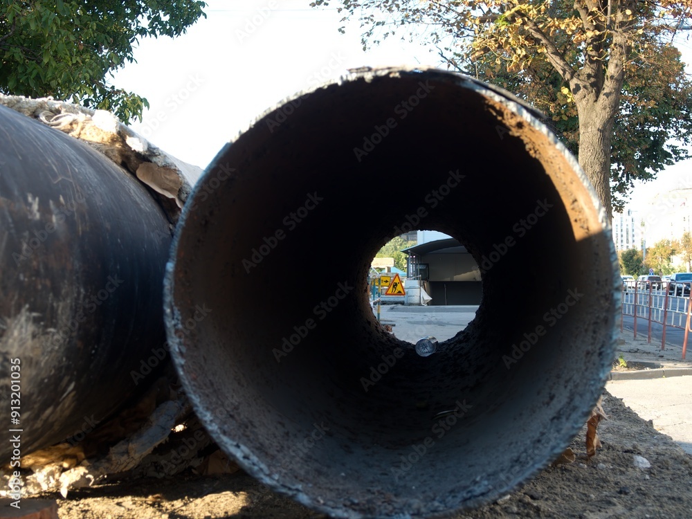 Large metal pipe on a city construction site highlighting urban ecology issues. Large metal pipe on a city construction site highlighting urban ecology issues.