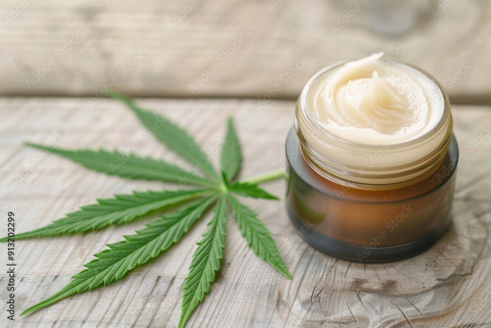 Natural cream in jar with hemp leaf on wooden background, highlighting organic skincare and wellness benefits. Natural cream in jar with hemp leaf on wooden background, highlighting organic skincare and wellness benefits.