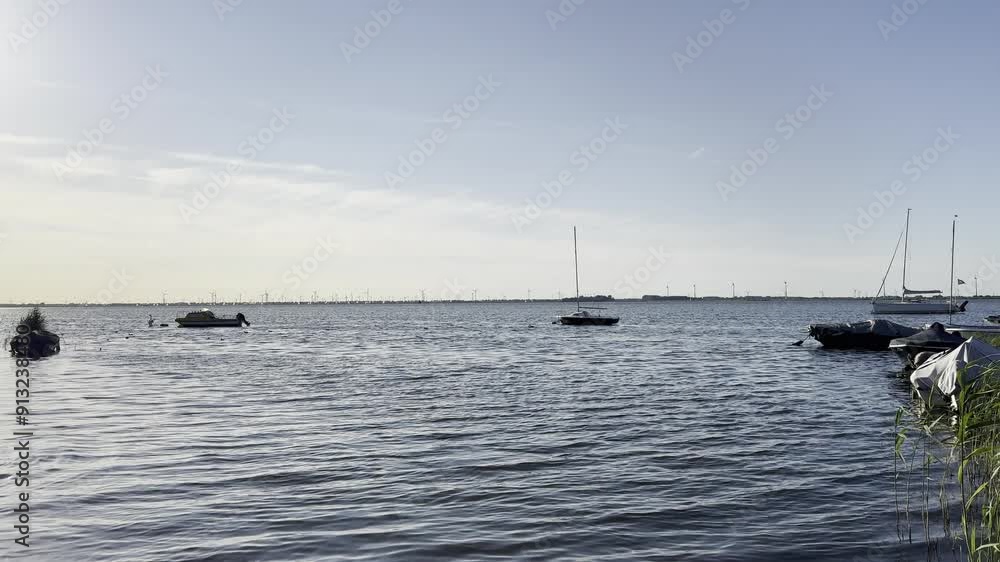 Shot from the lake in the municipality of Harderwijk, Netherlands. Wind turbines and boats in the background. Shot from the lake in the municipality of Harderwijk, Netherlands. Wind turbines and boats in the background.