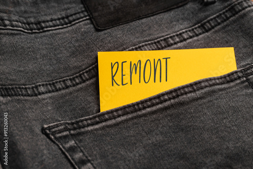 Yellow card with a handwritten inscription "Remont", inserted into the pocket of gray pants jeasnow (selective focus), translation: Renovation