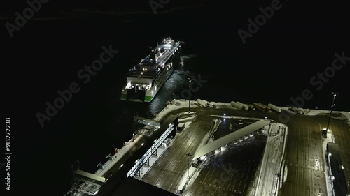 Helsinki.Finland-January 18.2022: Drone shot of a ship docking at Lansisatama in Helsinki Finland. Transportation. Wintertime. West harbor. Nighttime. Camera slowly moving backwards. photo