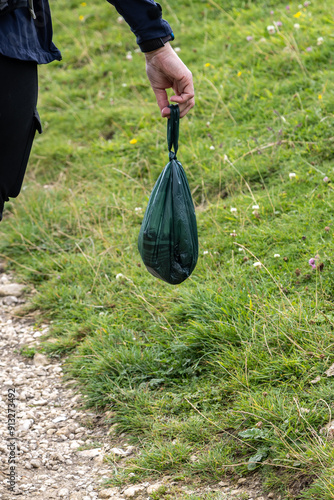 A close up of a womans hand holding a full dog poo bag photo