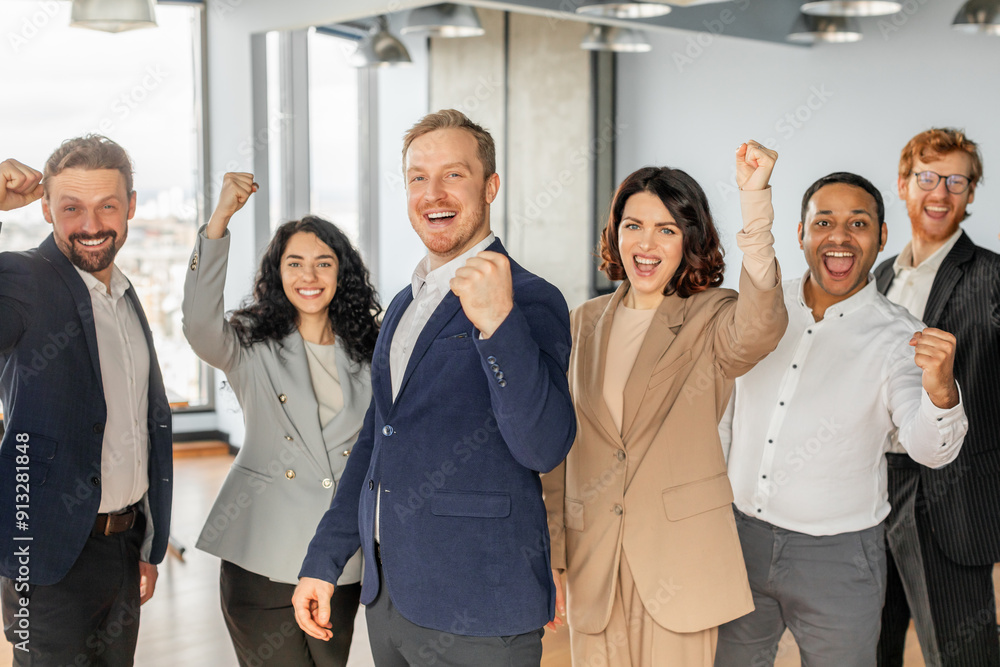 A diverse group of five business professionals stand in a modern office setting, with each person raising a fist in the air and smiling broadly, celebrating a successful achievement. A diverse group of five business professionals stand in a modern office setting, with each person raising a fist in the air and smiling broadly, celebrating a successful achievement.