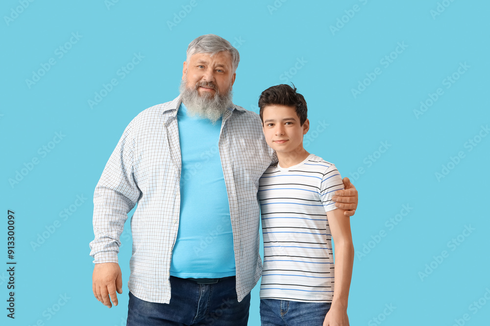 Happy grandfather with his cute grandson on blue background Happy grandfather with his cute grandson on blue background