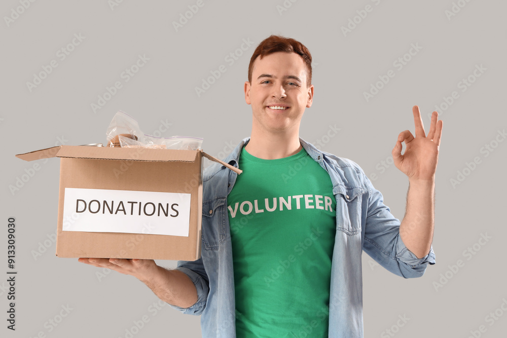 Male volunteer with donation box showing OK on light background Male volunteer with donation box showing OK on light background