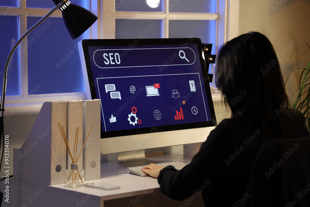 Woman using computer with abbreviation SEO in dark office Woman using computer with abbreviation SEO in dark office