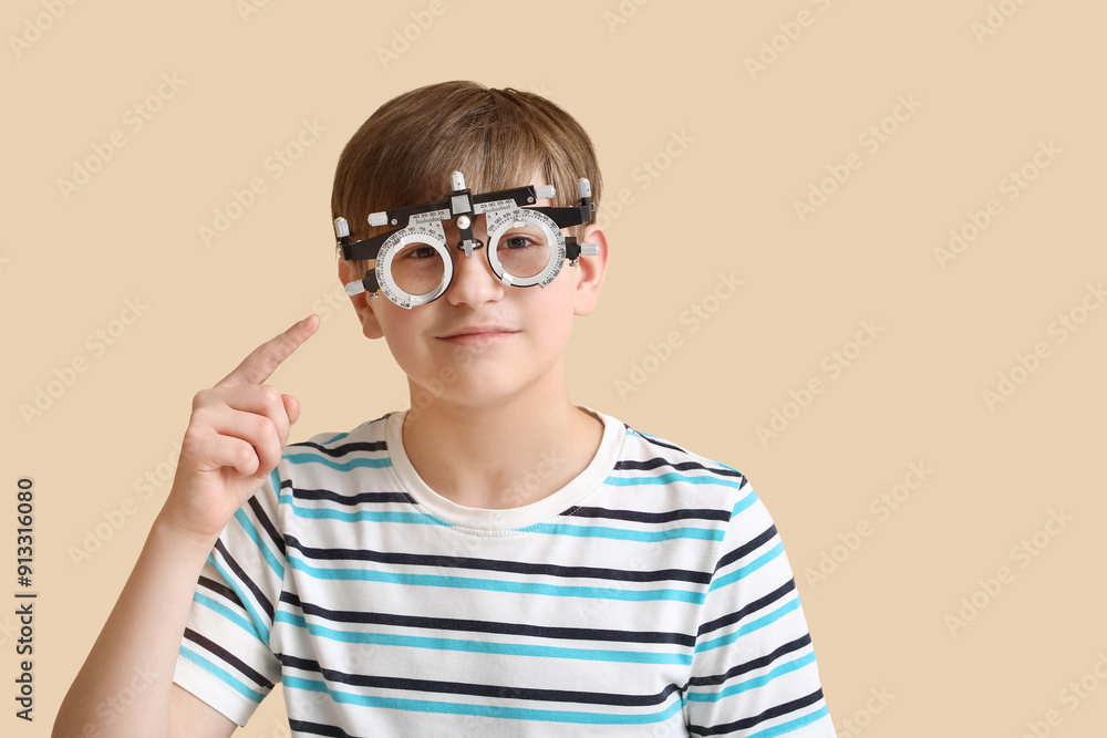 Little boy pointing at optical trial frame on beige background Little boy pointing at optical trial frame on beige background
