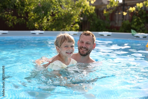 Happy father having fun with his daughter in swimming pool