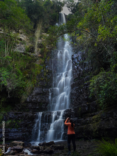 Travel woman photographing a waterfall in the middle of nature.