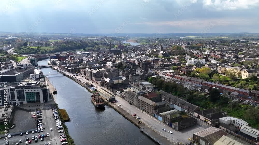 Drogheda, County Louth, Ireland, April 2023. Drone pushes forward, over the Boyne River with the Urban cityscape towards a street view with light traffic on a sunny day. Drogheda, County Louth, Ireland, April 2023. Drone pushes forward, over the Boyne River with the Urban cityscape towards a street view with light traffic on a sunny day.