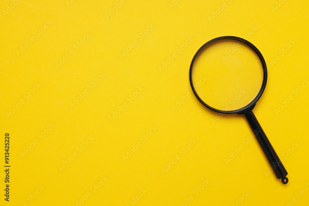 A magnifying glass in a black frame on a yellow background A magnifying glass in a black frame on a yellow background