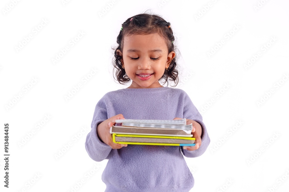 A smiling little Asian girl looks down at the book she is carrying, against a white background. A smiling little Asian girl looks down at the book she is carrying, against a white background.