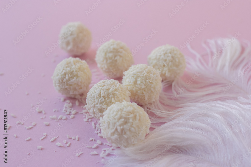 Top view of White Chocolate Candy With Coconut Topping On White Feather and pink background, sweet balls on plate flat lay with copy space. Romantic gift for celebration or anniversary Top view of White Chocolate Candy With Coconut Topping On White Feather and pink background, sweet balls on plate flat lay with copy space. Romantic gift for celebration or anniversary