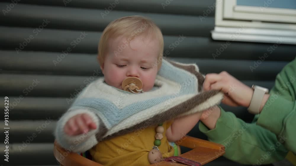 Adult Woman Dressing Baby In Sweater Adult Woman Dressing Baby In Sweater