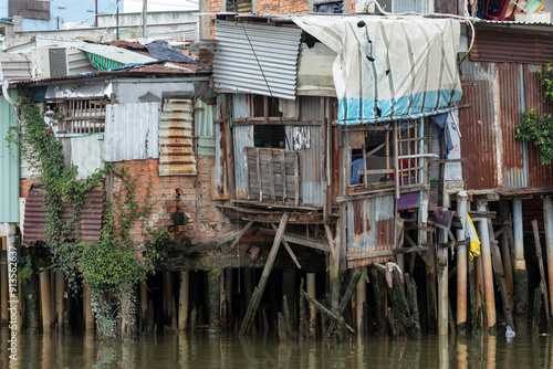 Shanty house along Kenh Te canal in Ho Chi Minh City, Vietnam. House is built from iron sheets and supported by wooden piles into the water. photo