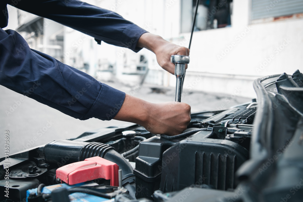 Mechanic using wrench while working on car engine outside the service center , Repair and service. Mechanic using wrench while working on car engine outside the service center , Repair and service.