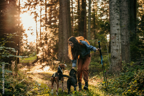 A smiling woman with a small dog hiking in the forest photo