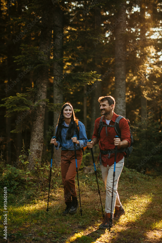 Young fit and healthy man and woman walking with sticks and backpack during hike in the woods Young fit and healthy man and woman walking with sticks and backpack during hike in the woods