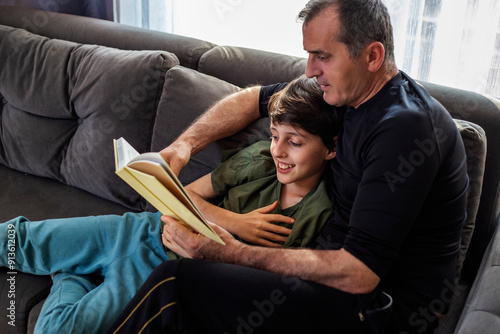 Father and son reading together on the couch photo