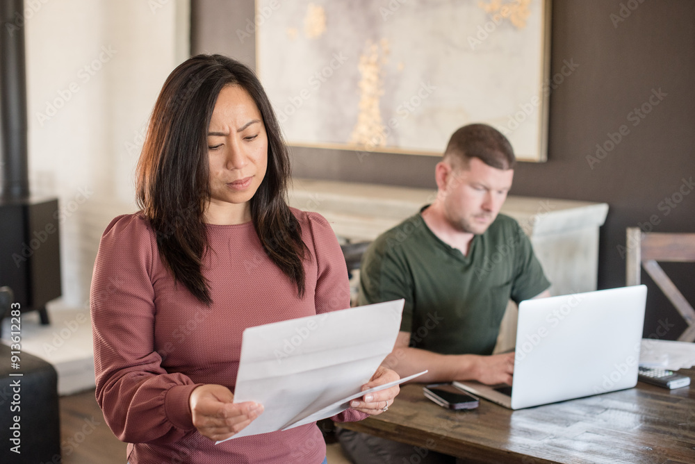 Wife looking at bill with husband in the background Wife looking at bill with husband in the background