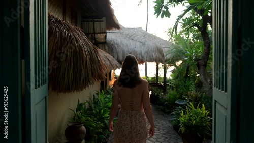 Tourist Woman Walking Towards The Restaurant At The Hotel Accommodation During Sunrise In Bali, Indonesia. Tracking Shot photo