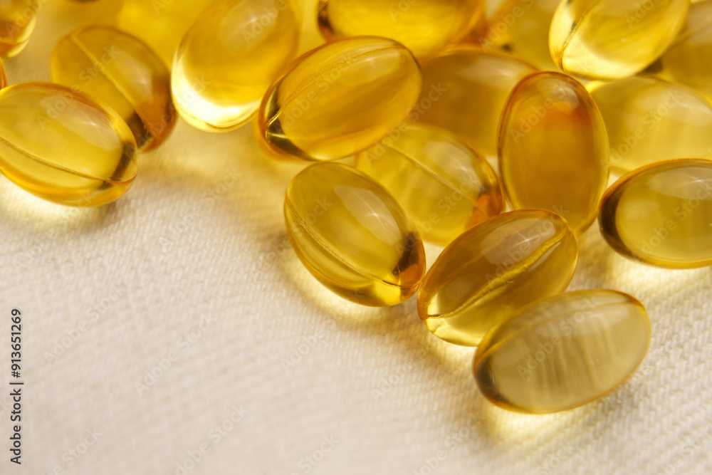 Dietary supplement softgel capsules on soft fabric background. Golden yellow pills Dietary supplement softgel capsules on soft fabric background. Golden yellow pills