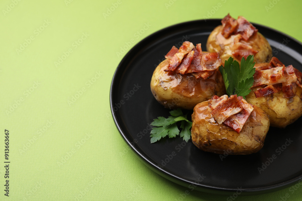 Delicious baked potatoes with bacon and parsley on green background, closeup. Space for text Delicious baked potatoes with bacon and parsley on green background, closeup. Space for text