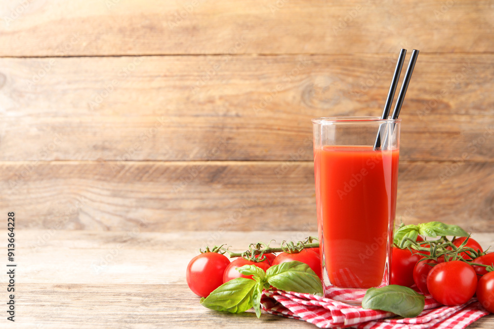 Tasty tomato juice in glass with basil leaves and fresh vegetables on wooden table, space for text Tasty tomato juice in glass with basil leaves and fresh vegetables on wooden table, space for text