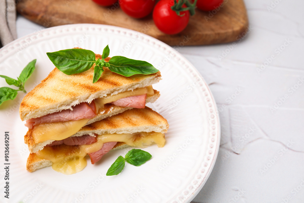Pieces of toasted bread with melted cheese, ham and basil on white table Pieces of toasted bread with melted cheese, ham and basil on white table