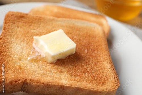 Delicious toasted bread slices with butter on table, closeup