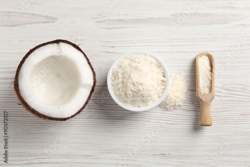 Fresh coconut flour in bowl, scoop and nut on white wooden table, flat lay