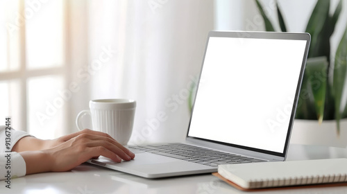Close up of hand using laptop touchpad with blank screen, white cup and notebook