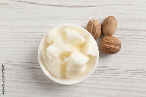 Canvas Print Natural shea butter in bowl and nuts on wooden table, top view