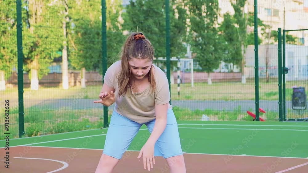 Cute Girl kid playing basketball alone on street city sports playground. The concept of sports, active recreation, after school, workout and hobby Cute Girl kid playing basketball alone on street city sports playground. The concept of sports, active recreation, after school, workout and hobby