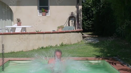 Middle-aged man dives into a swimming pool, cannonball style