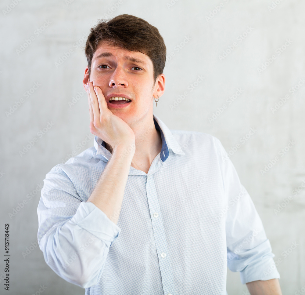 Young guy holding his cheek with toothache Young guy holding his cheek with toothache
