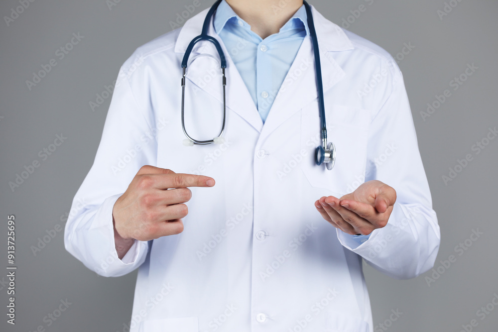 Doctor pointing at something on grey background, closeup Doctor pointing at something on grey background, closeup