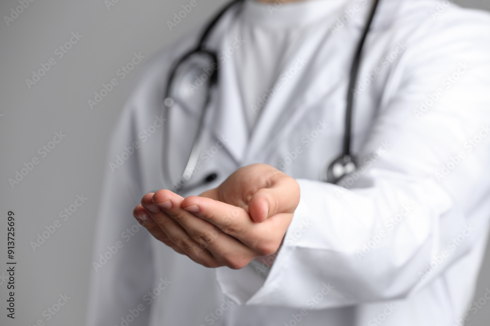 Doctor holding something on grey background, closeup Doctor holding something on grey background, closeup