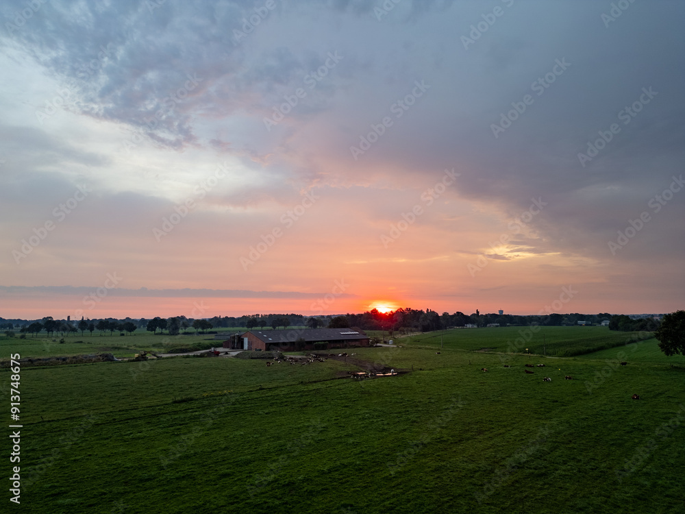 Obraz premium A stunningly beautiful sunset with warm and vibrant hues gracefully casting light over a peaceful countryside field