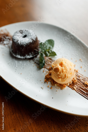 delicious dessert with creamy frosting, chocolate, fresh nuts, and fragrant herbs on a beautiful white plate in a cozy nice restaurant