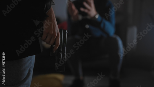 Foto A suspicious man handcuffed on a sofa indoors, a policewoman standing with a gun, implying an arrest scene