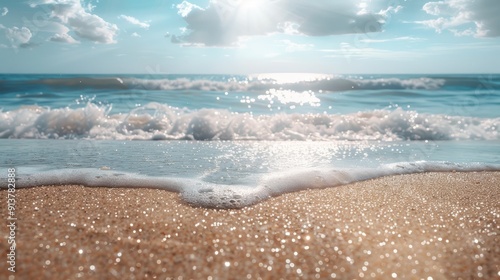  A sandy beach with waves lapping the shore, sun shining on shimmering water, and clouds in the azure sky