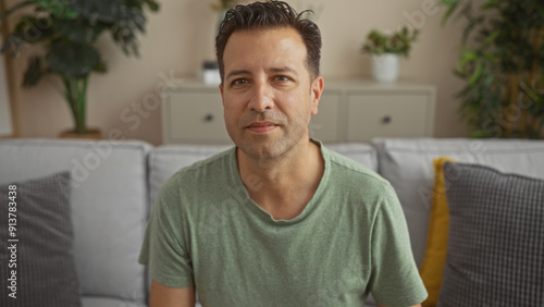 Bild auf Leinwand Handsome hispanic man indoors in a comfortable living room setting, staring at t