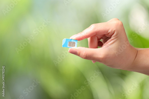 Woman with SIM card against blurred green background, closeup, Space for text