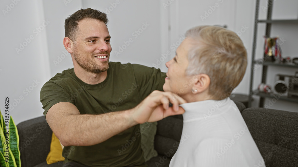 Smiling man and older woman sitting together in a modern living room enjoying a relaxed conversation. Smiling man and older woman sitting together in a modern living room enjoying a relaxed conversation.