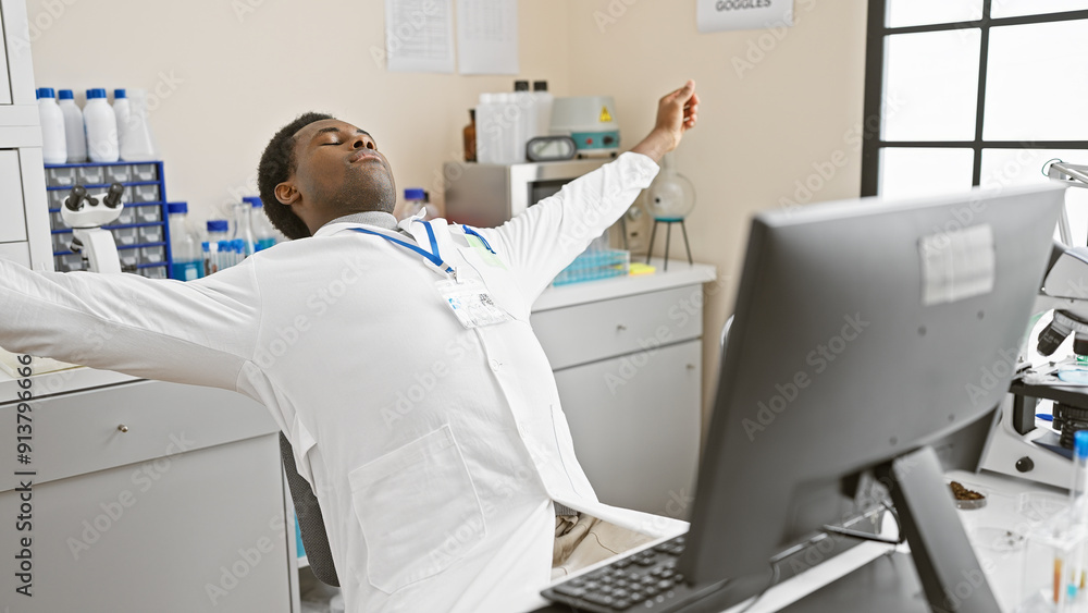 Fototapeta premium African man stretching in a modern laboratory setting, surrounded by scientific equipment, indoors.