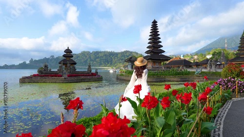 4k slow motion video.Young female tourist at Pura ulun danu bratan temple in Bali, Indonesia.In the morning and the beautiful sky

